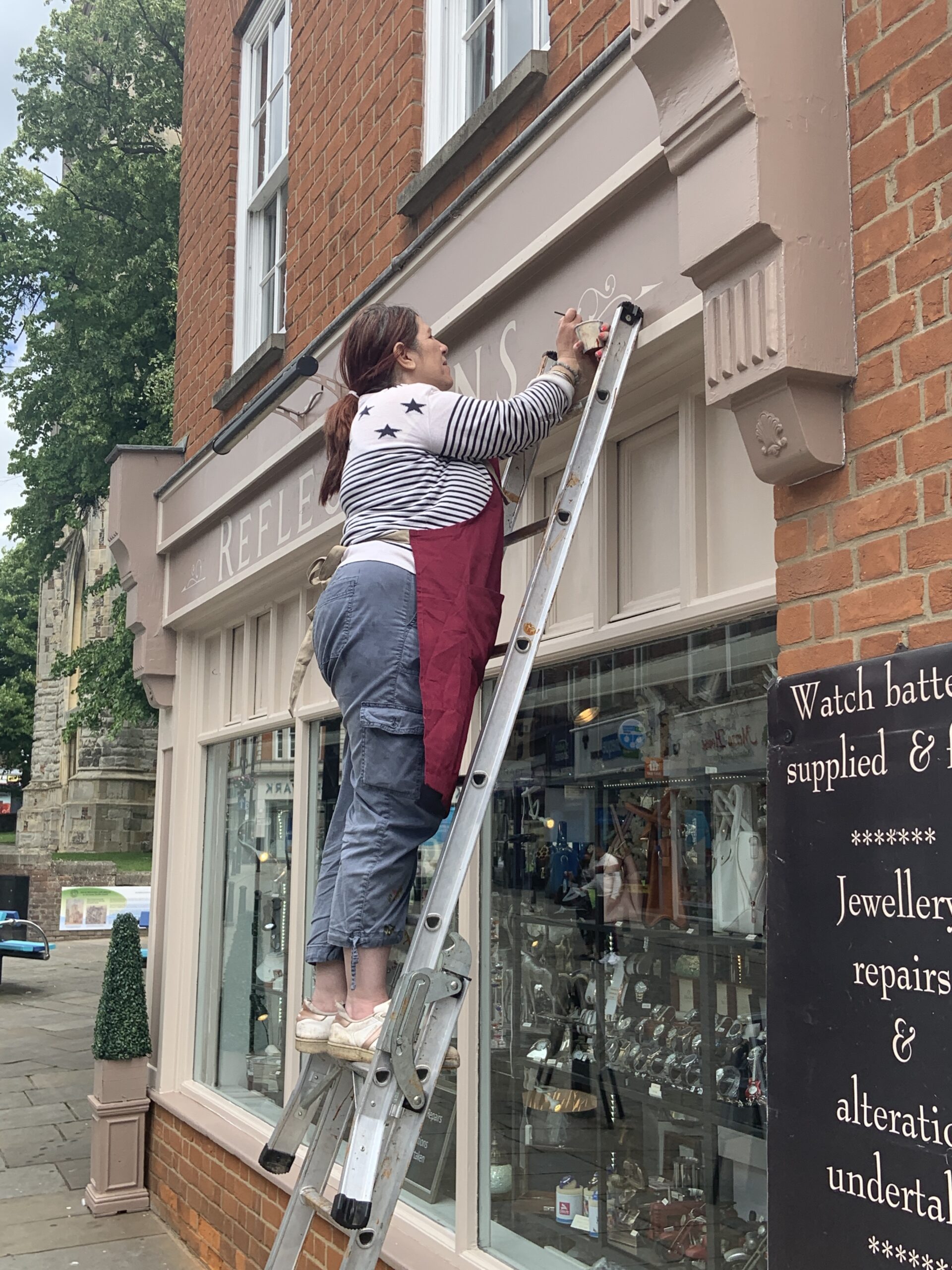 Painting a shop sign up a ladder